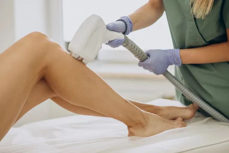 Aesthetic specialist performing laser hair removal on a patient's lower leg